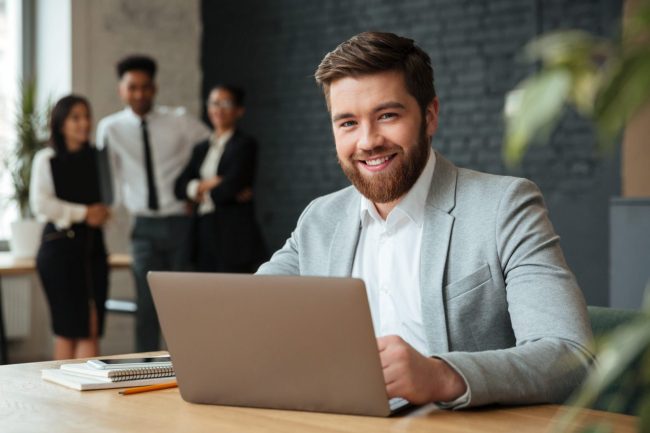 Photo of smiling businessman with laptop illustrates blog "Business Loans vs Business Credit Cards: Which Is the Best Option?"