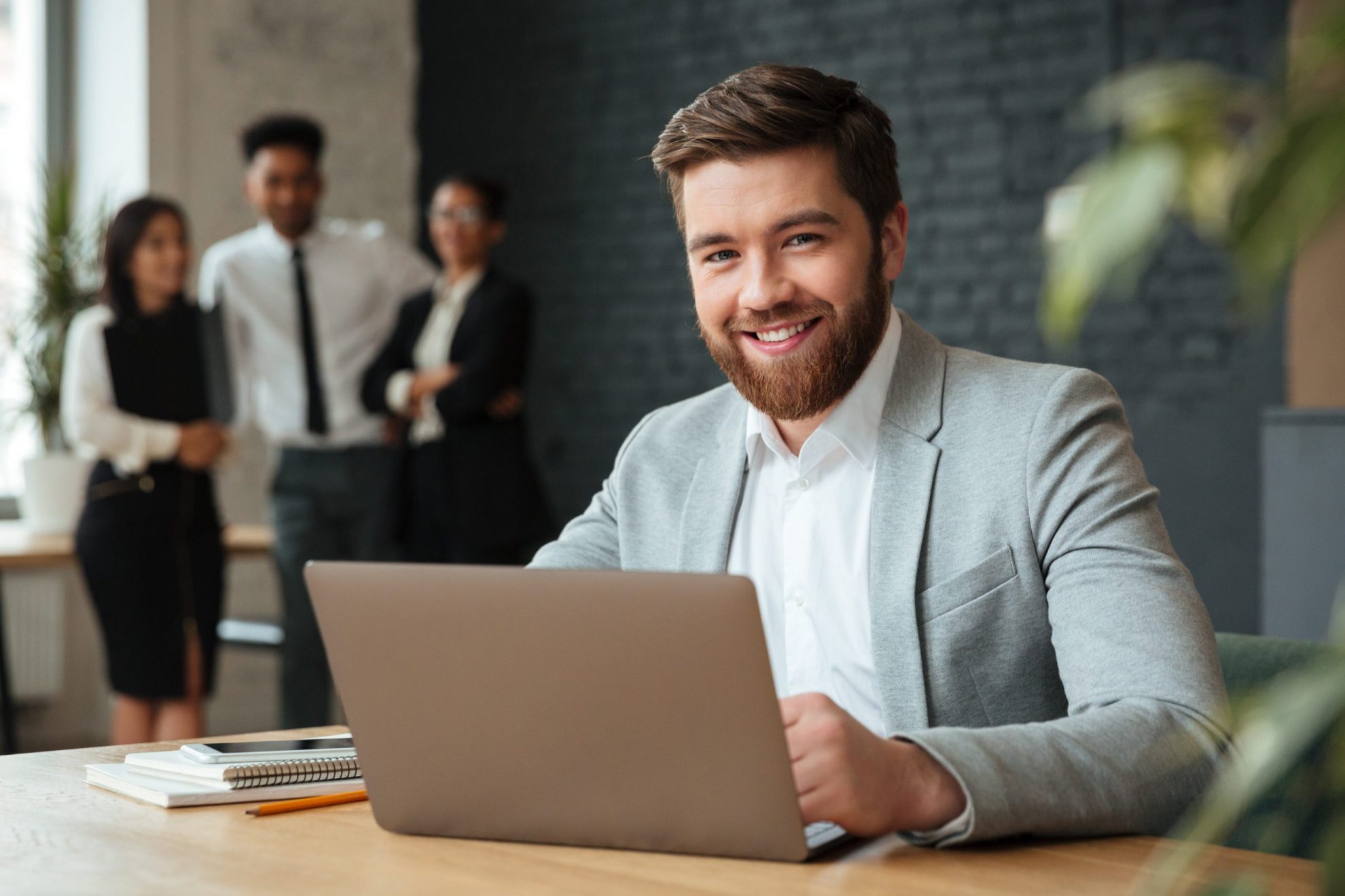 Photo of smiling businessman with laptop illustrates blog "Business Loans vs Business Credit Cards: Which Is the Best Option?"