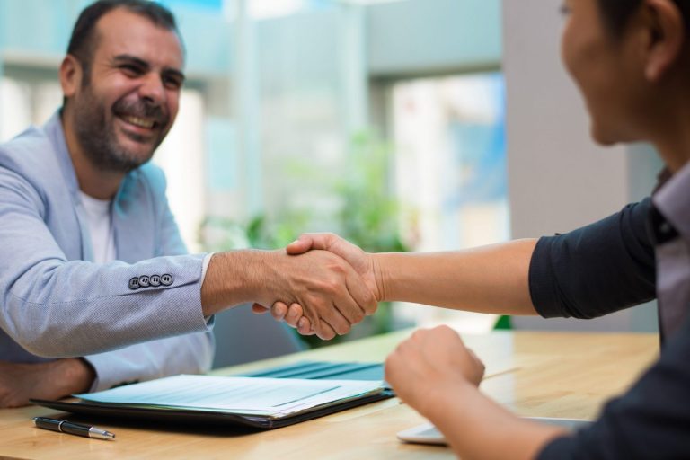 Photo of two men shaking hands illustrates blog: "Photo of confident businessman illustrates blog: "4 Tips for Refinancing Your Commercial Loan"