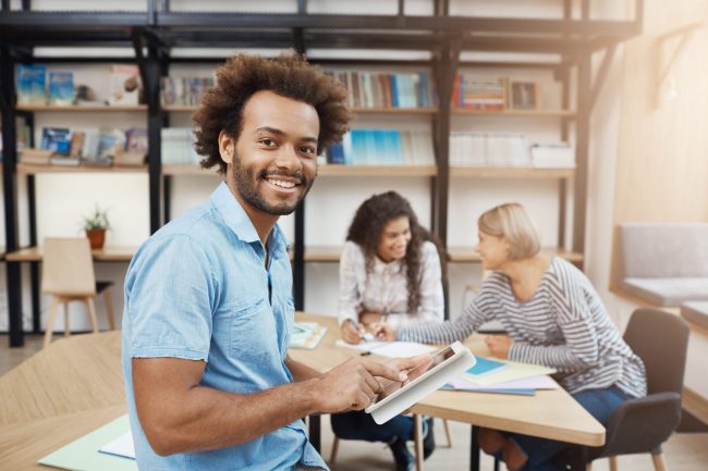 Photo of smiling man holding tablet illustrates blog: "What Are Revenue-Based Loans?"
