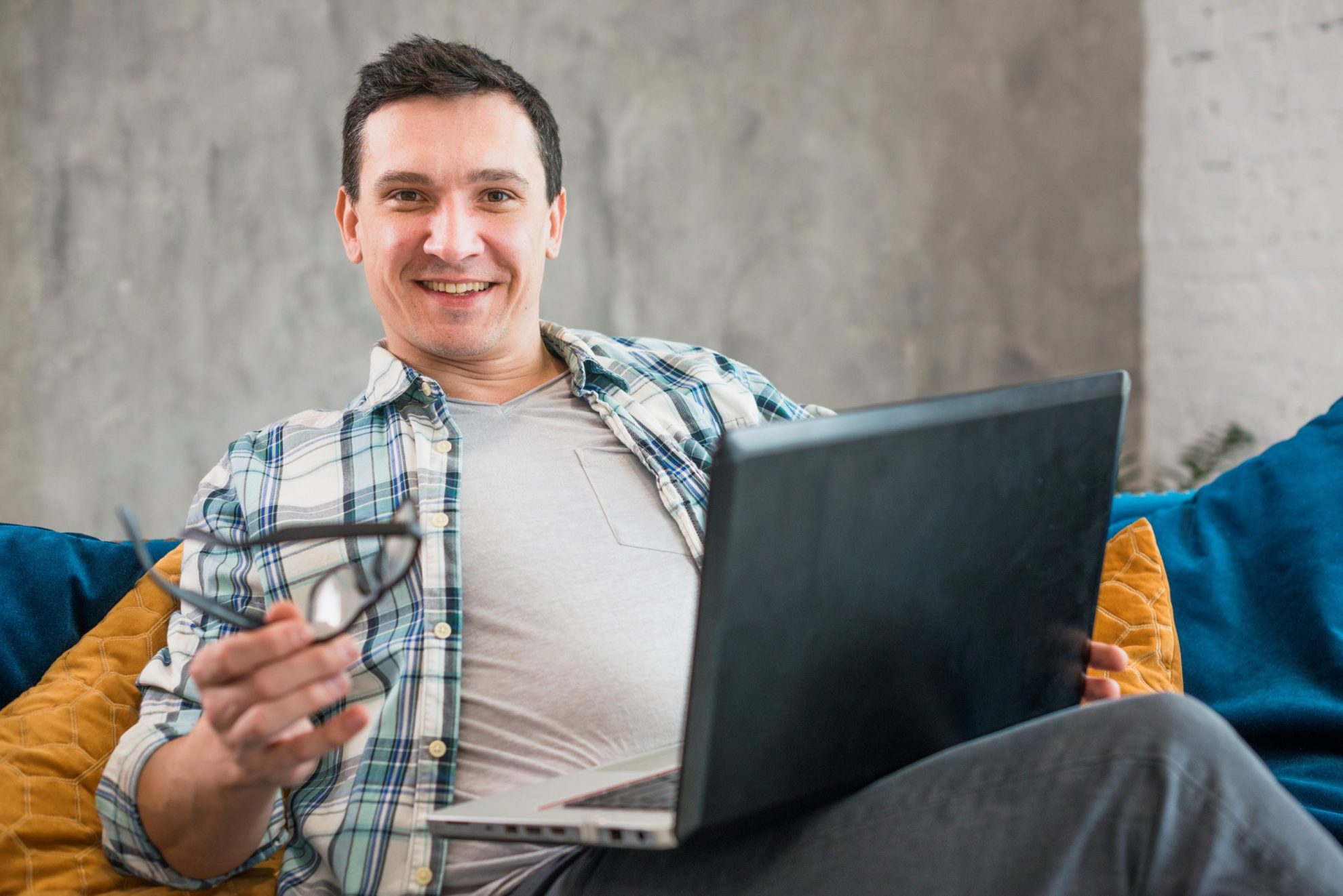 Photo of smiling man with laptop illustrates blog: "4 Reasons to Refinance Your Business Loan"