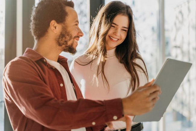 Man and woman looking at tablet illustrates blog "How Long Are SBA Loans?"