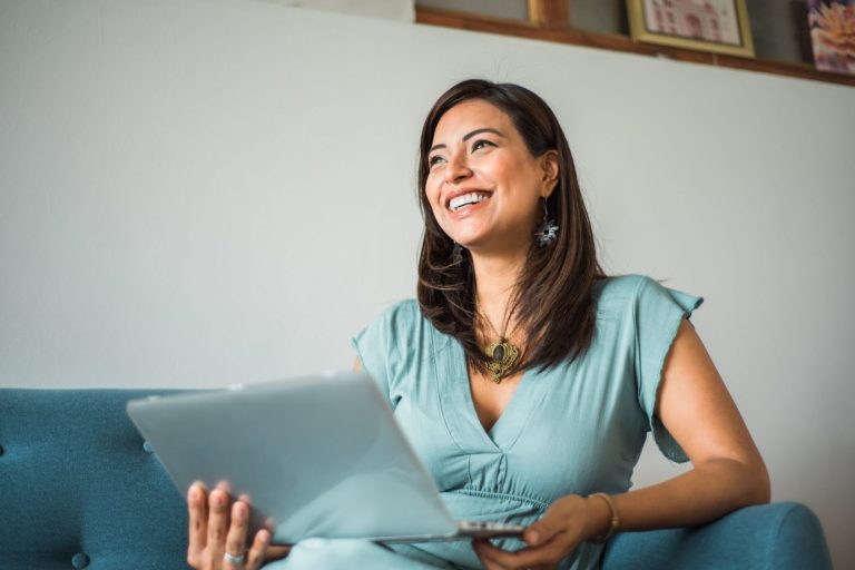 Photo of smiling woman with laptop illustrates blog: "SBA Loan Requirements: a Quick Guide"