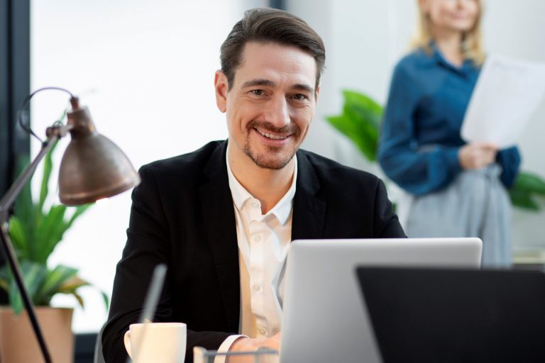Man in business attire sitting behind laptop illustrates blog "Understanding the Language of Business Loans: A Glossary"