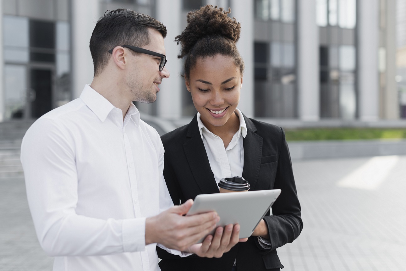 Man and woman looking at tablet illustrate blog "Do Businesses Have Credit Scores?"'