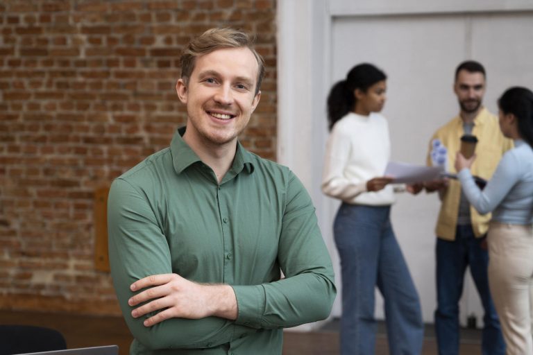 Smiling man with arms crossed across chest and two women in the background illustrates blog "Recourse vs Non-Recourse Loans"