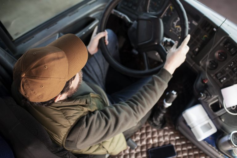 Trucker holding steering wheel of truck illustrates blog "Business Loans for Trucking Companies: What You Need To Know"