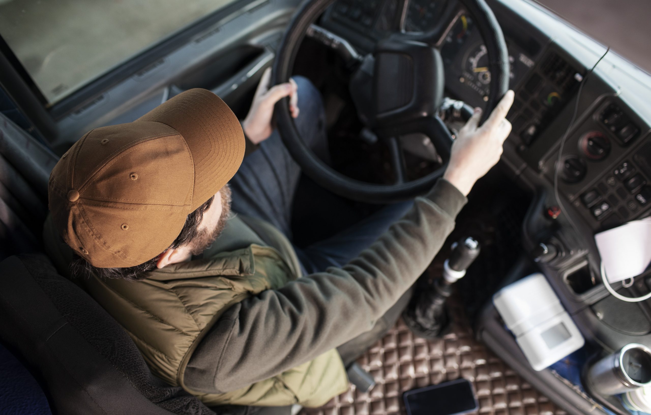 Trucker holding steering wheel of truck illustrates blog "Business Loans for Trucking Companies: What You Need To Know"